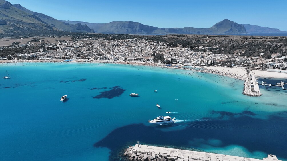 A coastal town with a clear blue sea, boats, and a mountainous backdrop. 5