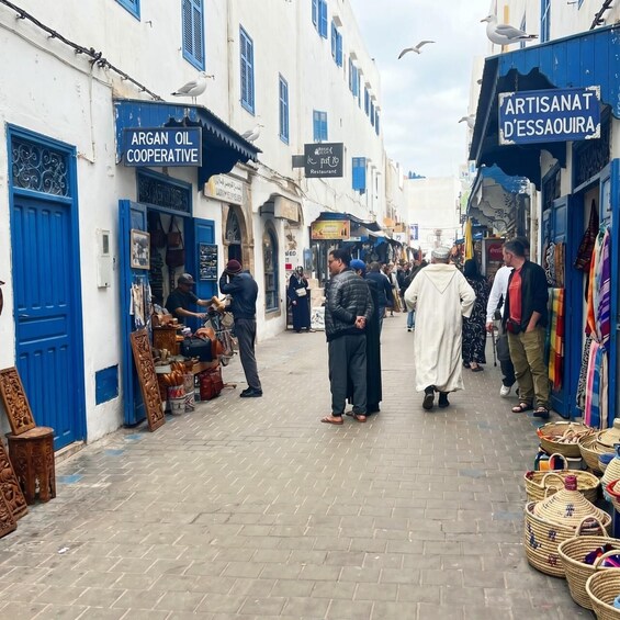 A bustling street with shops, including a cooperative and a restaurant, and a variety of goods displayed outside. 4