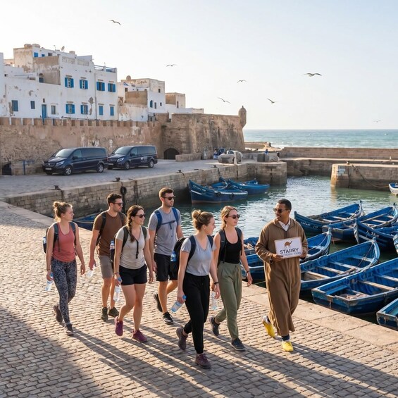 A group of people walking along a waterfront promenade with boats docked nearby. 3