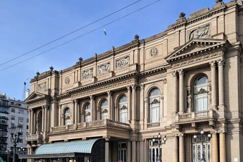 En historisk byggnad med utsmyckad arkitektur, stora fönster och en framträdande entré. 3