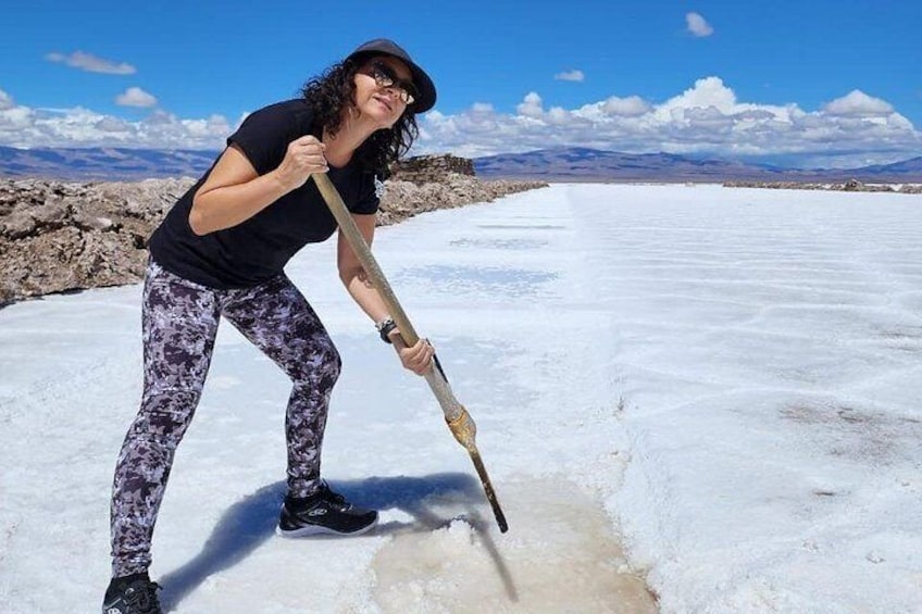 Una persona utilizza uno strumento su una superficie piana e bianca, con un cielo sereno e montagne lontane sullo sfondo. 4