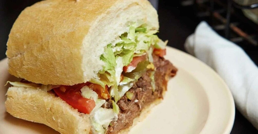 A sandwich with a crusty bun, lettuce, tomatoes, and a beef patty. 1