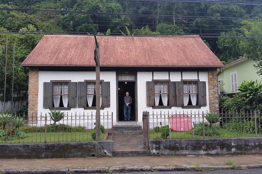 A two-story house with a red roof, white walls, and wooden shutters. 4