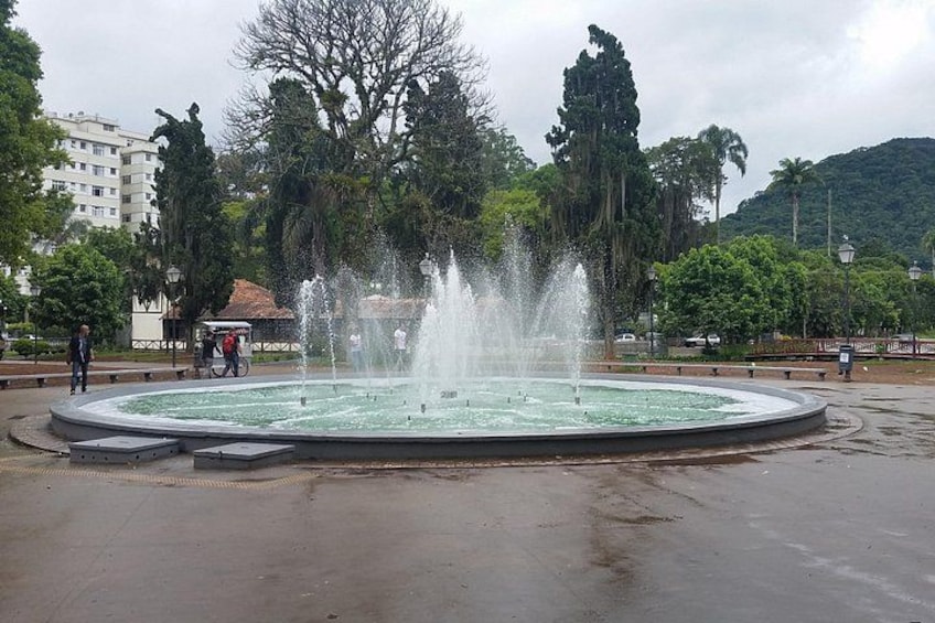 A circular fountain with water jets in the center, surrounded by a paved area with benches. 3