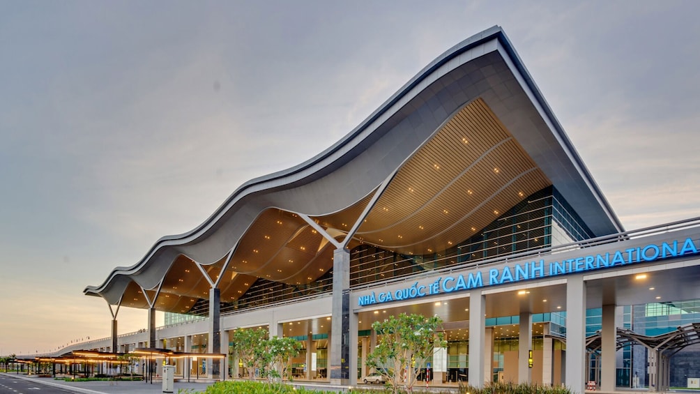 Un bâtiment moderne doté d’un toit incurvé et d’une enseigne indiquant « NHÃ GA QUÃC TÃE CAM RANH INTERNATIONAL ». 5