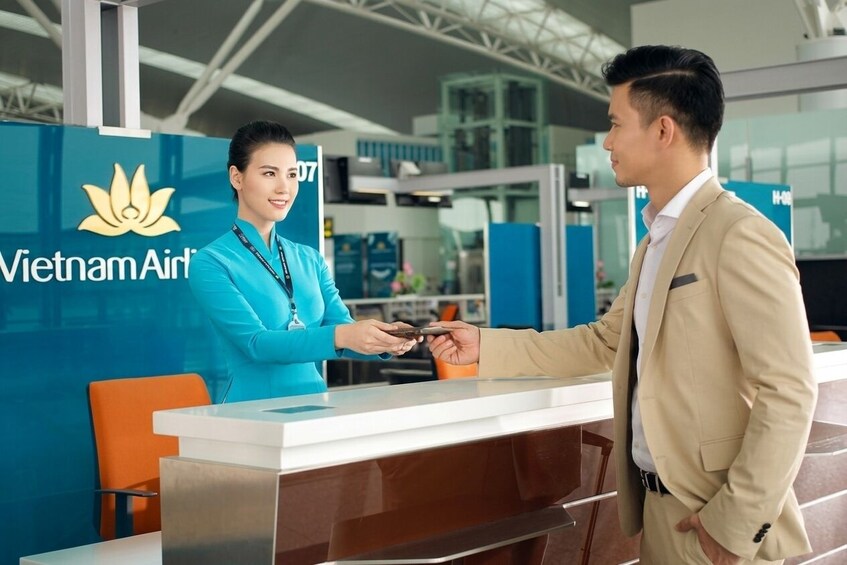 Un homme et une femme se tiennent devant le comptoir d’enregistrement d’un aéroport, sur lequel on peut voir le logo de Vietnam Airlines. 3