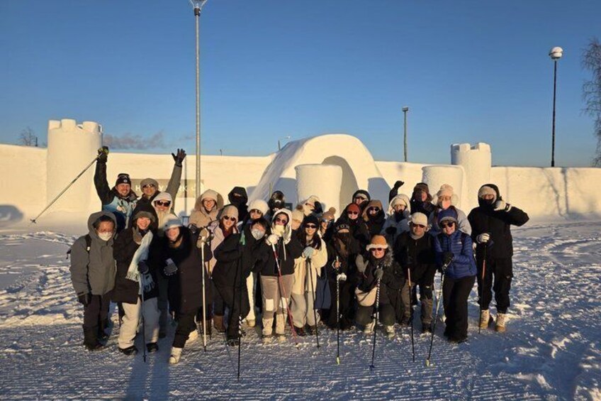 Een groep mensen in winterkleding poseert voor een kasteelachtig gebouw met sneeuw. 1