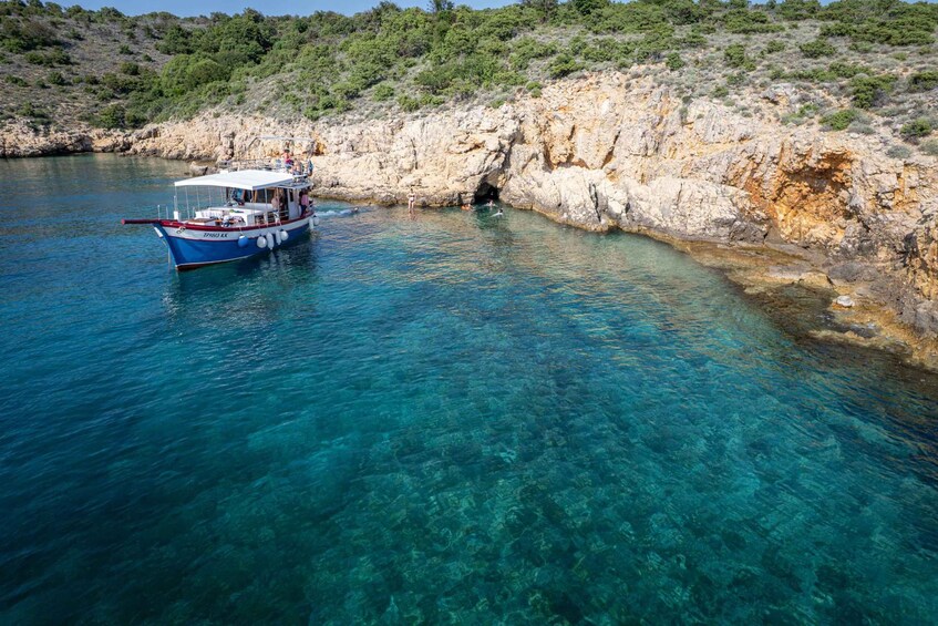 A boat anchored near a rocky shoreline with clear blue water. 5