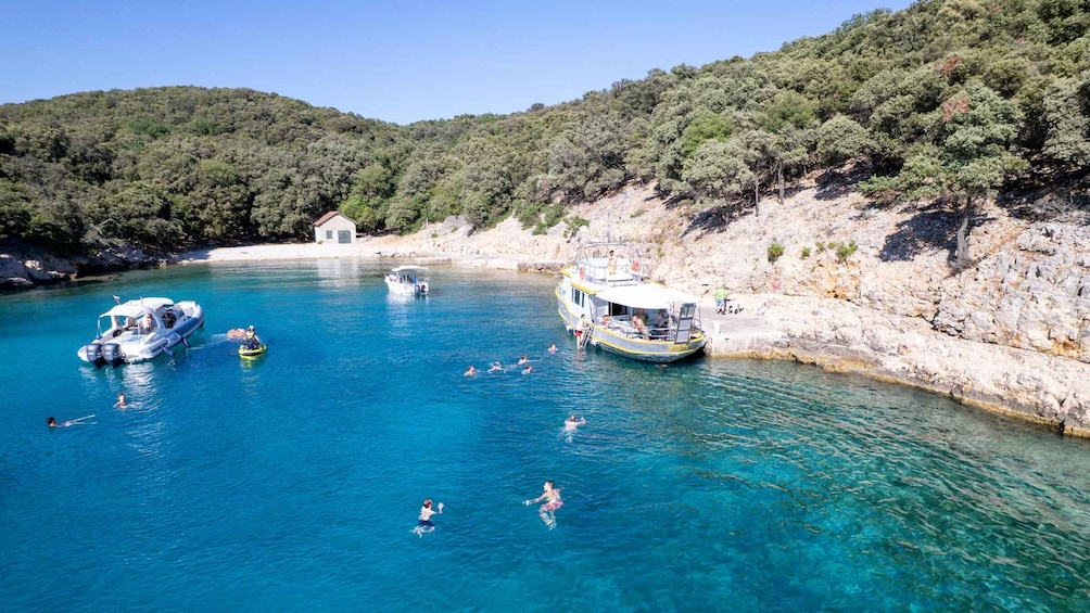 A coastal area with clear blue waters, boats, and people swimming and snorkeling. 4