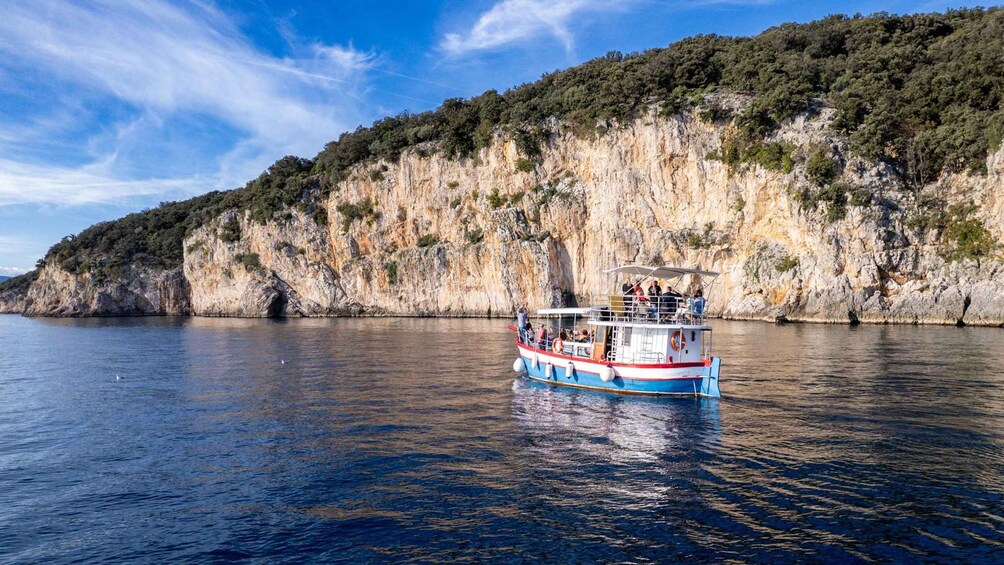 A boat on calm water with a rocky cliff in the background. 2