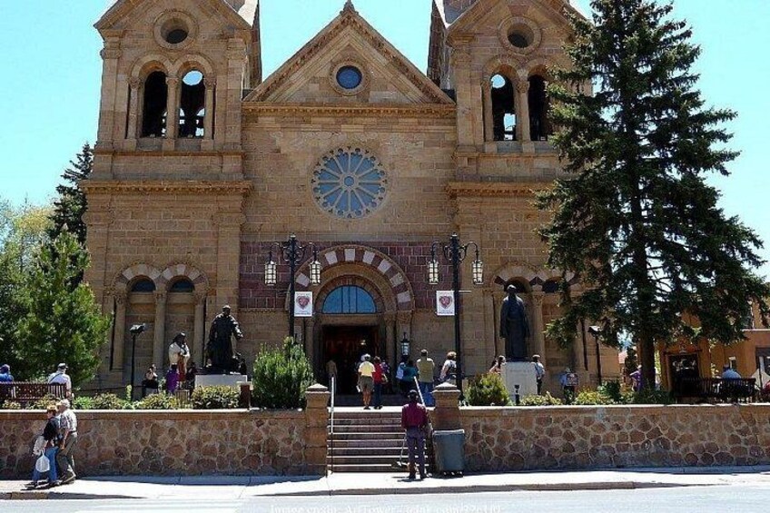 A historic church with a large circular stained glass window, a bell tower, and statues on the facade. 4