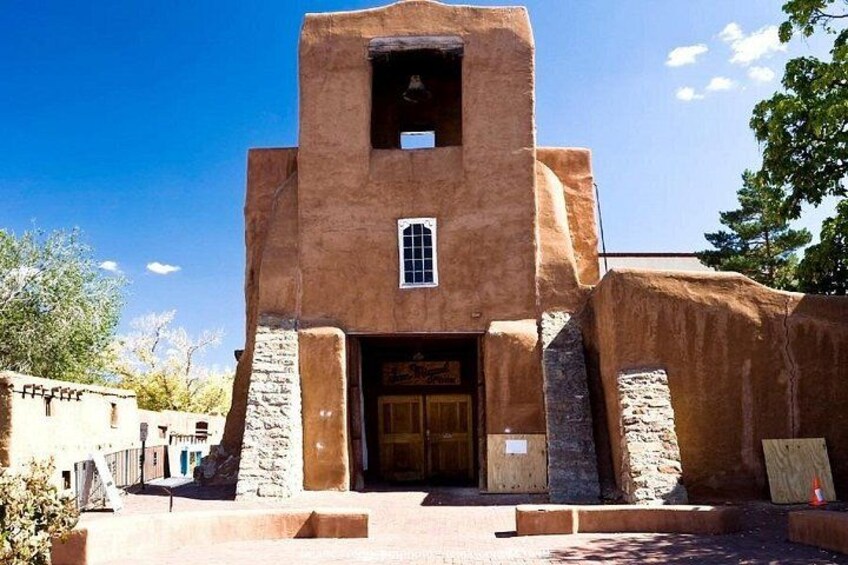 A rustic building with a bell tower, a wooden door, and stone pillars. 3