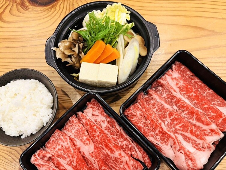 A meal with rice, beef, vegetables, and tofu on a wooden table. 2