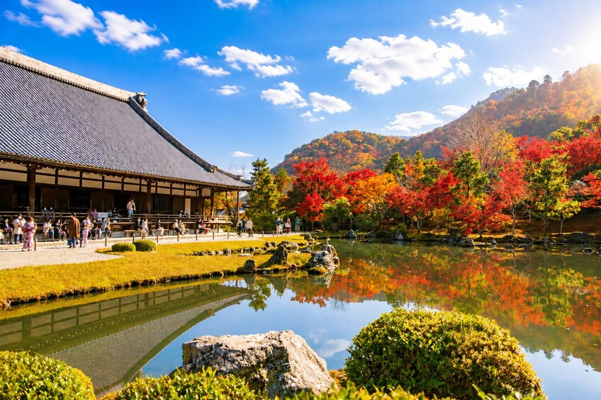 A traditional Japanese building with a reflection in a pond surrounded by autumn foliage. 5