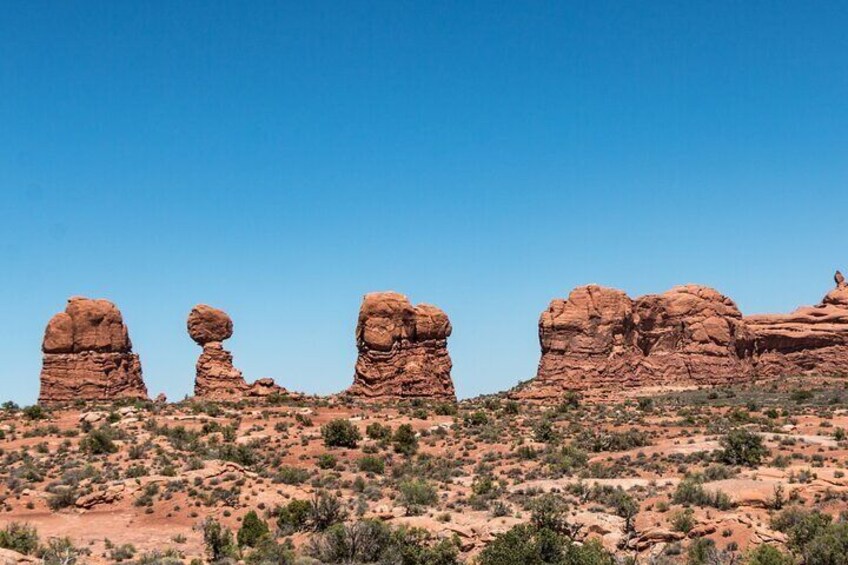 A desert landscape with red rock formations and sparse vegetation. 5