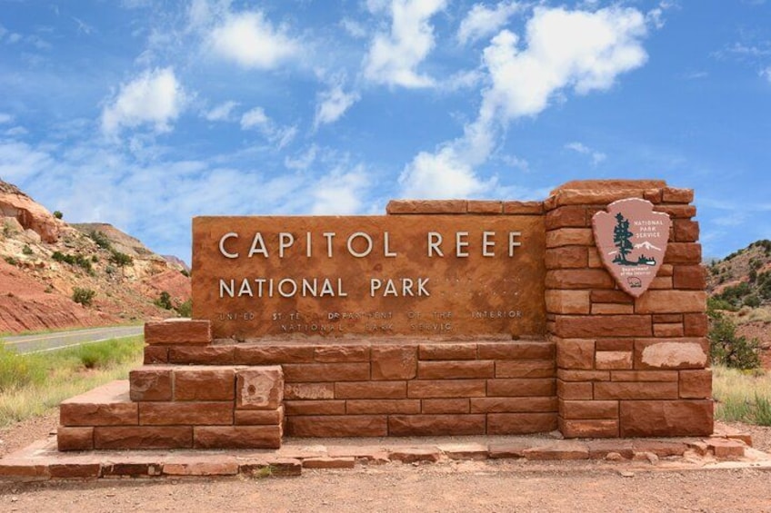 Un panneau indiquant l’entrée du parc national de Capitol Reef, avec une structure en pierre et un logo. 1