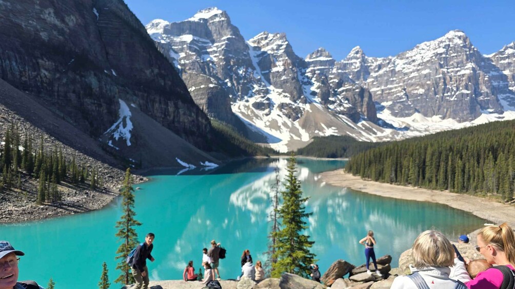 A turquoise lake surrounded by snow-capped mountains and dense forests. 3
