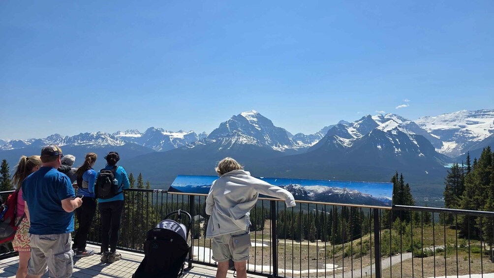 A group of people observing a mountain landscape from a viewing platform. 5