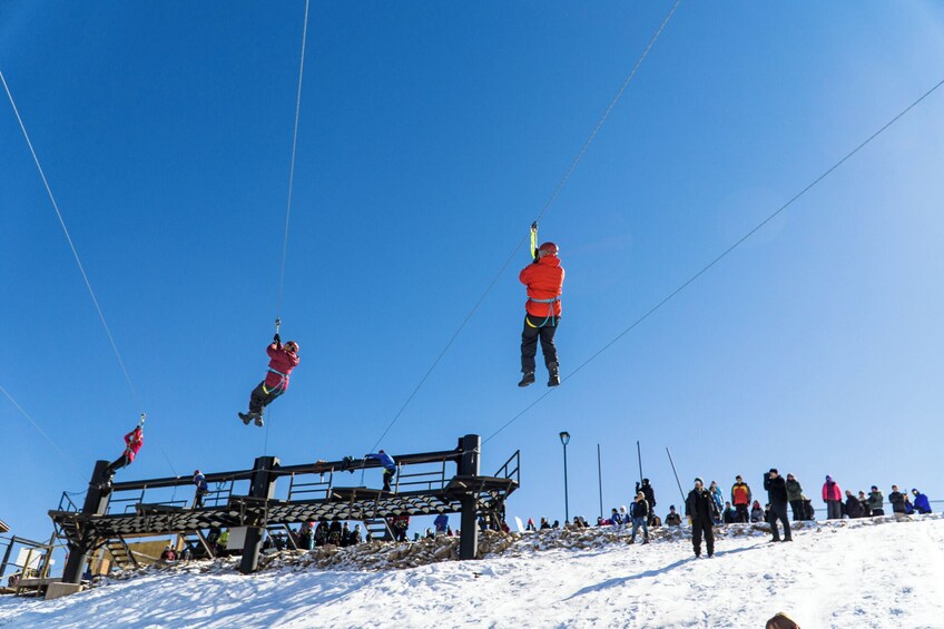 A ski lift with people in motion, a snowy landscape, and a clear blue sky. 5