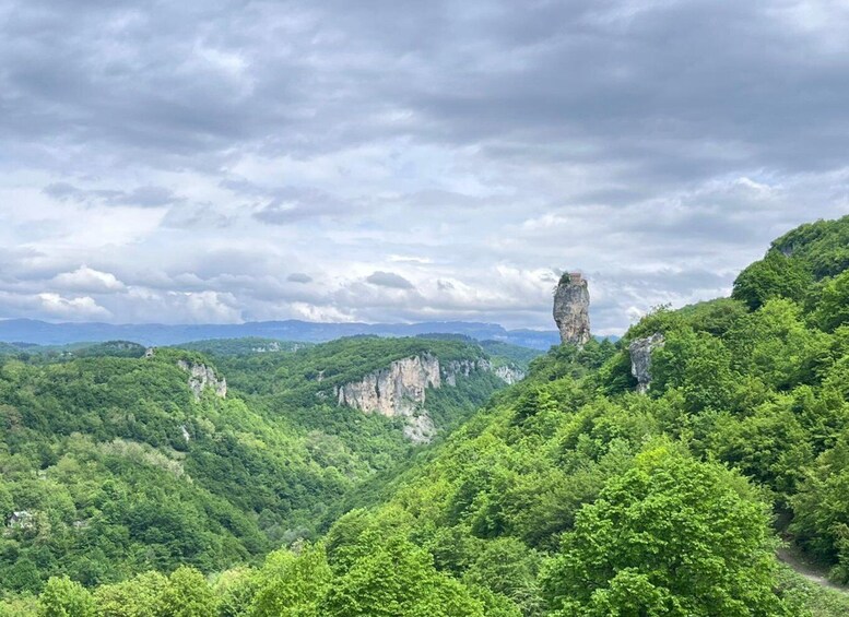 A lush green valley with prominent limestone cliffs and a distinctive rock formation. 1