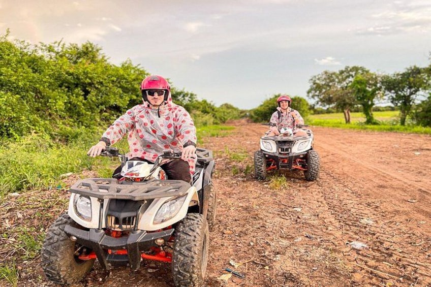Dos personas conduciendo cuatrimotos por un camino de tierra con vegetación al fondo. 5