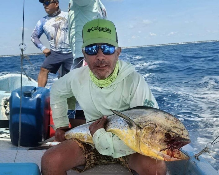 A person holding a large fish on a boat with another person in the background. 5