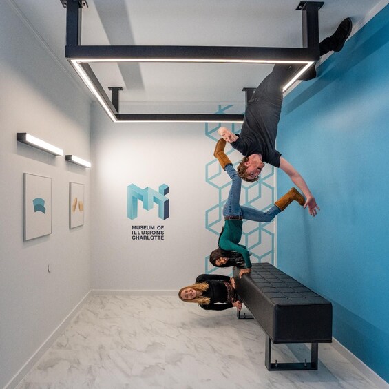 An art installation at the Museum of Illusions in Charlotte, featuring a person performing an acrobatic stunt on a bench. 5