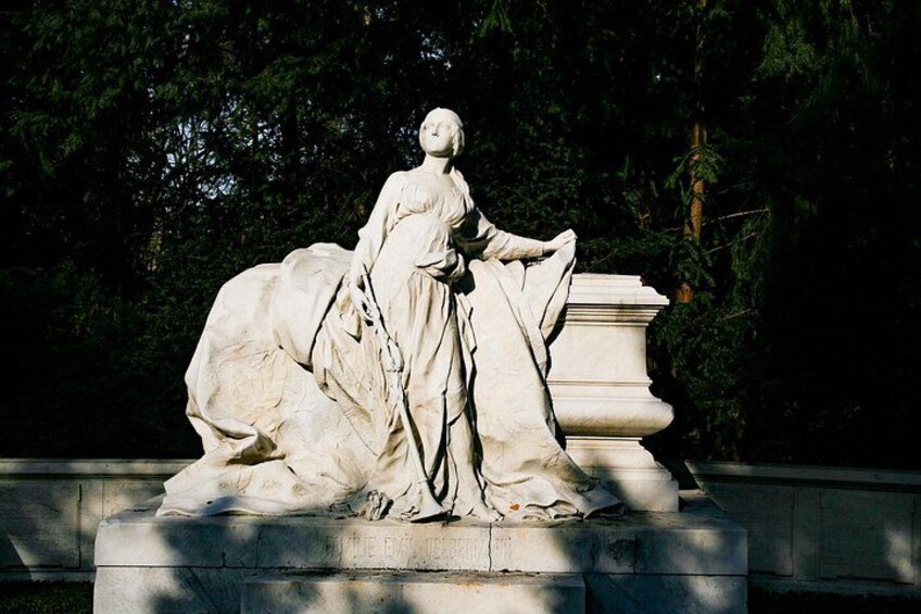 A statue of a woman in a dress, standing on a pedestal with a horse. 4