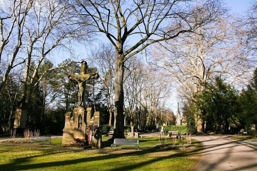 A cemetery with a large cross monument, trees, and a clear sky. 1