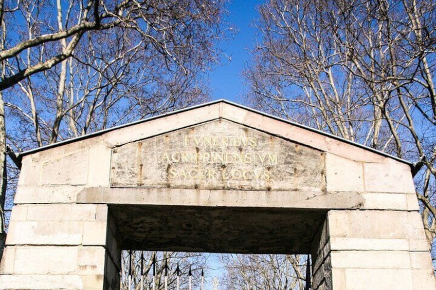 A stone structure with carved text, surrounded by leafless trees. 5
