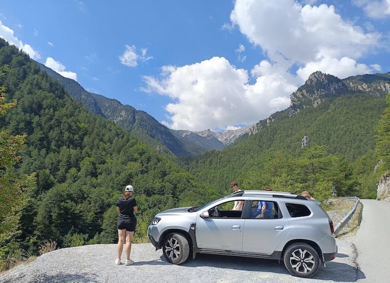 A silver SUV parked on a gravel path with a mountainous landscape in the background. 1