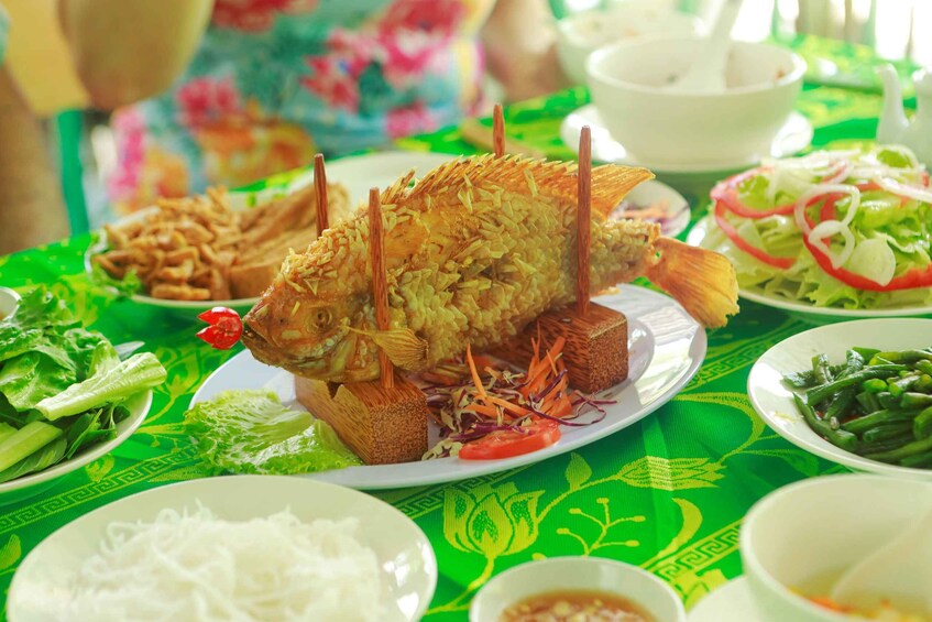 A meal with a whole fish on a plate, surrounded by various dishes and a green tablecloth. 1