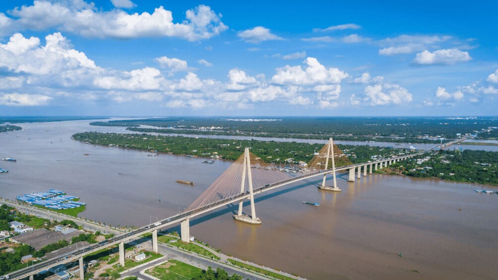 A large suspension bridge over a wide river with a clear sky and scattered clouds. 2