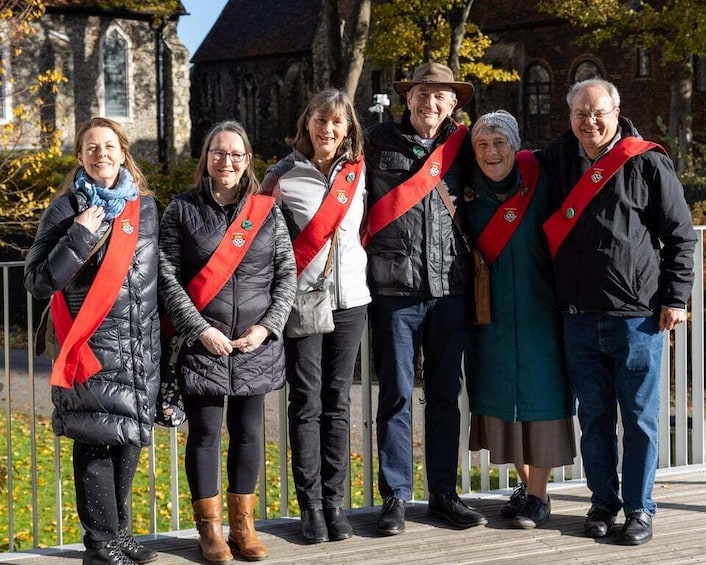 A group of people standing on a wooden deck with a church in the background. 5