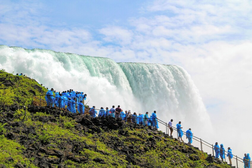 Ein großer Wasserfall mit Menschen, die auf einer felsigen Klippe stehen. 1