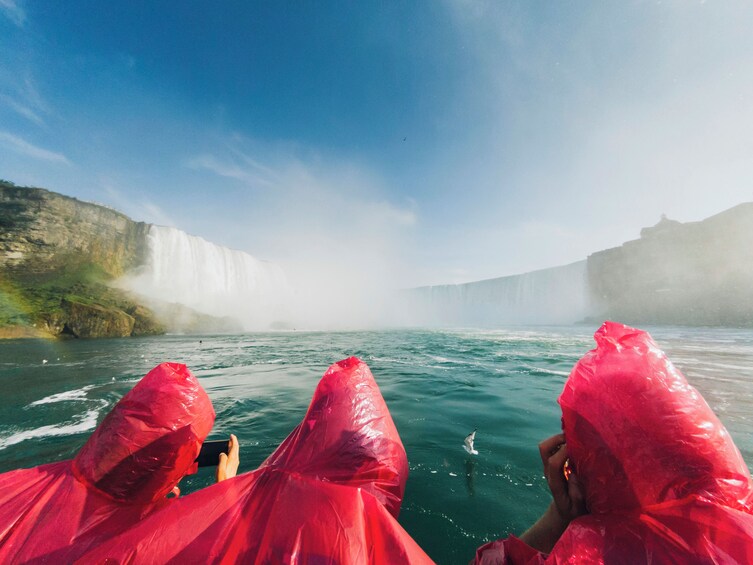 Eine Person in einem roten Regenmantel fotografiert einen Wasserfall. 3
