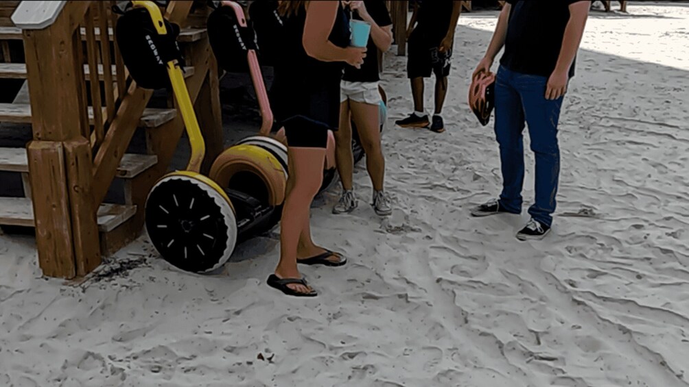 A sandy beach with a wooden structure and a person holding a blue cup. 4