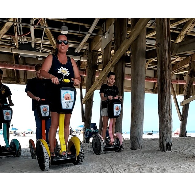 A person riding a Segway on a sandy beach under a wooden structure. 5