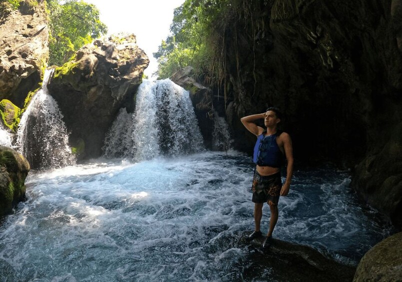 A waterfall in a rocky gorge with a person standing in the water. 5
