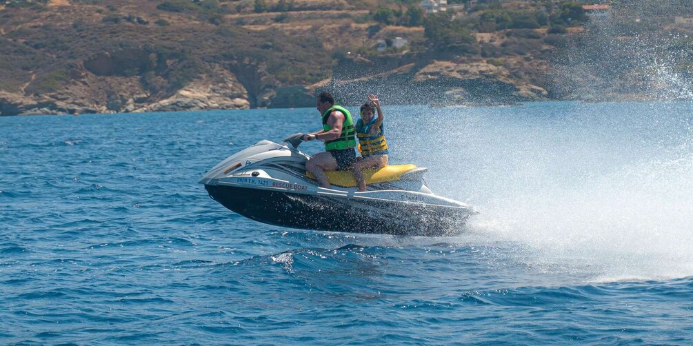 A person jet-skiing on a body of water with a rocky shoreline in the background. 2