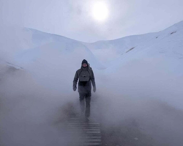 A person walking on a snow-covered path in a foggy, mountainous area. 5