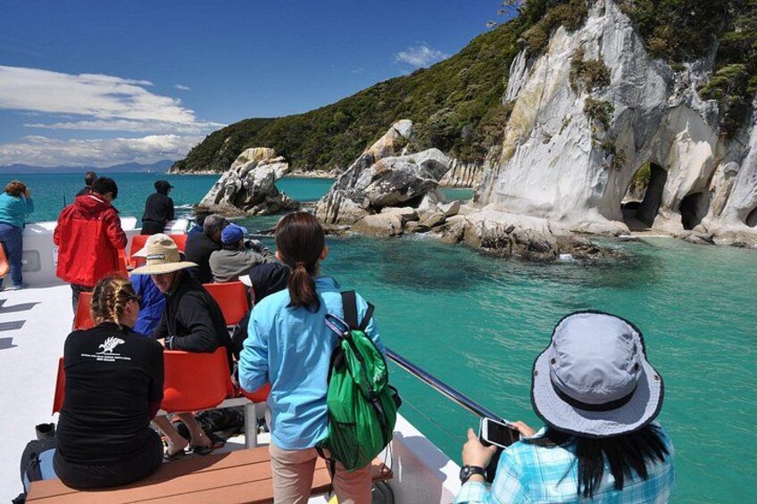 A boat with people on board, rocky cliffs, and clear turquoise water. 4