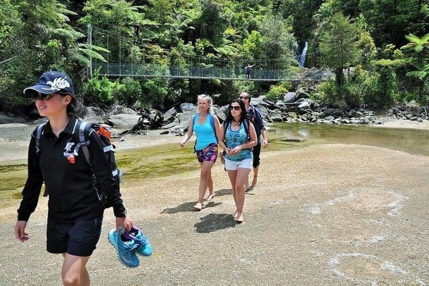 A group of people walking along a riverbank with greenery in the background. 5