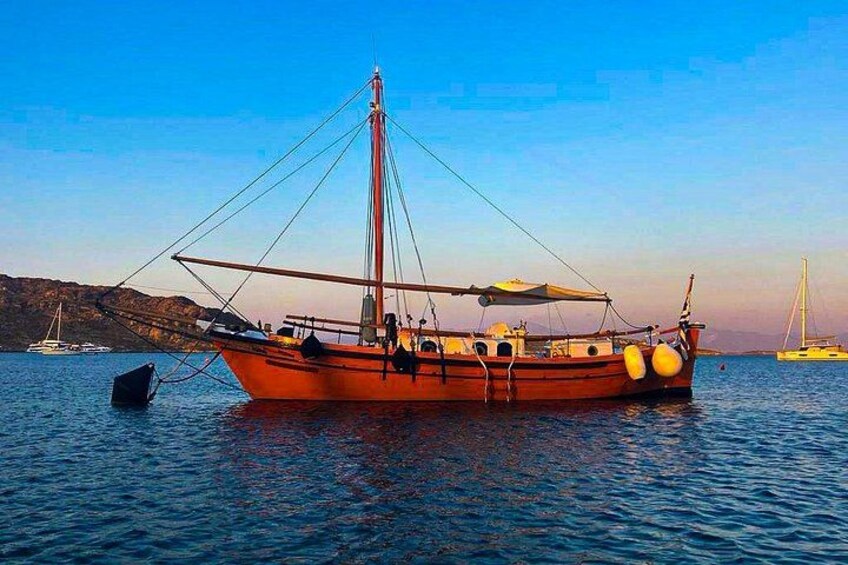 A red fishing boat anchored in calm waters with a clear sky and distant hills. 2