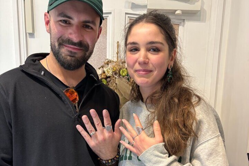 Two people standing indoors, one wearing a cap and the other holding a ring. 1
