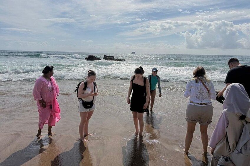 A group of people standing on a beach with waves in the background. 5