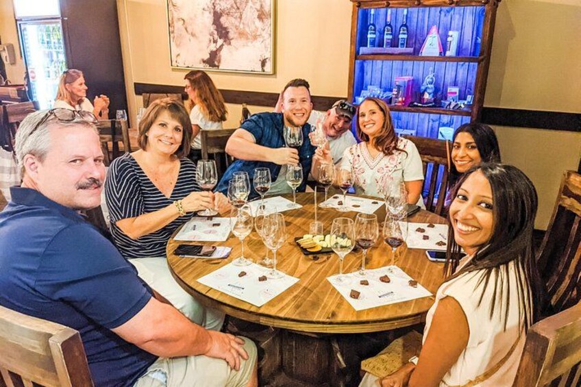 A group of people seated around a round table with wine glasses and menus. 2