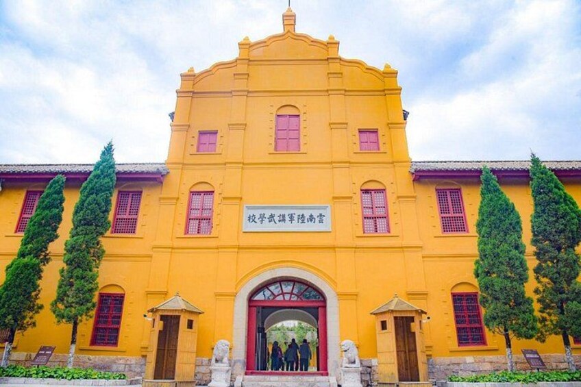 A yellow building with red windows and a sign in a foreign language. 5