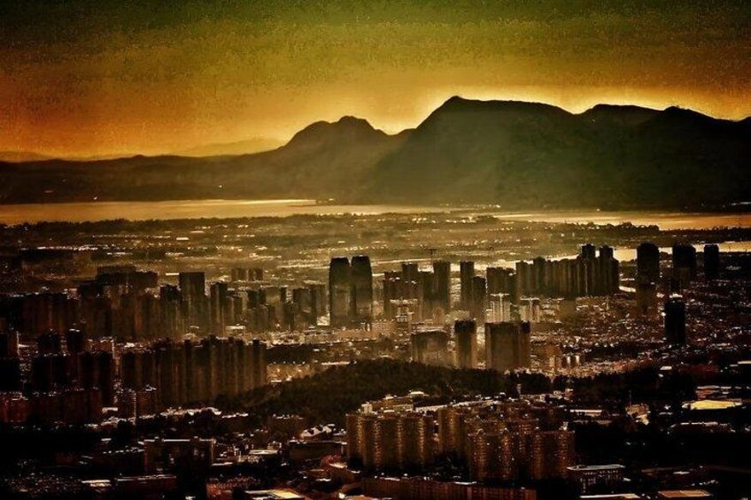 A cityscape with high-rise buildings, a river, and mountains in the background. 3