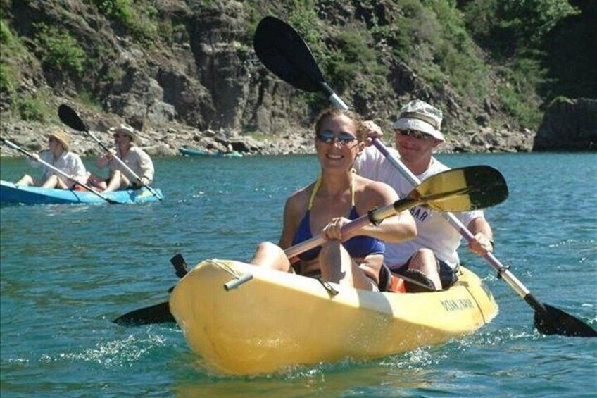 A yellow kayak on calm water with people paddling. 3